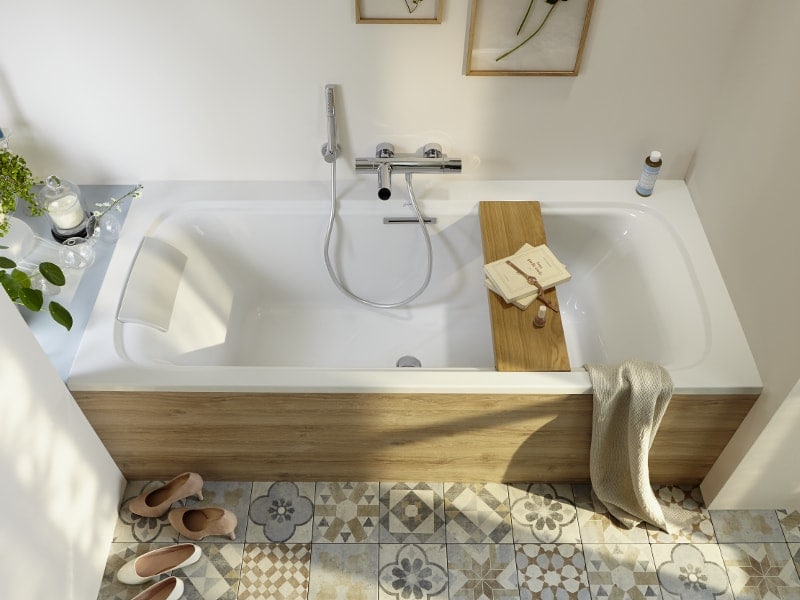 Un tablier de baignoire en bois avec avec des murs peints en blanc et un sol avec des motifs colorés