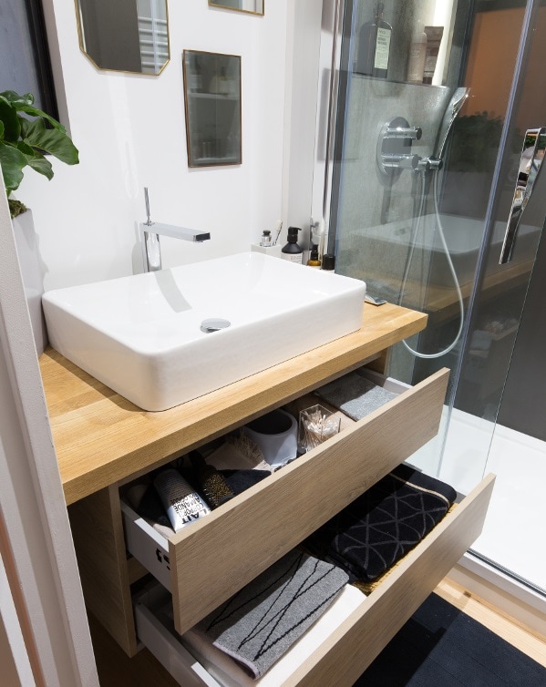 Une salle de bains avec une douche et une vasque blanche sur un plan-vasque en bois