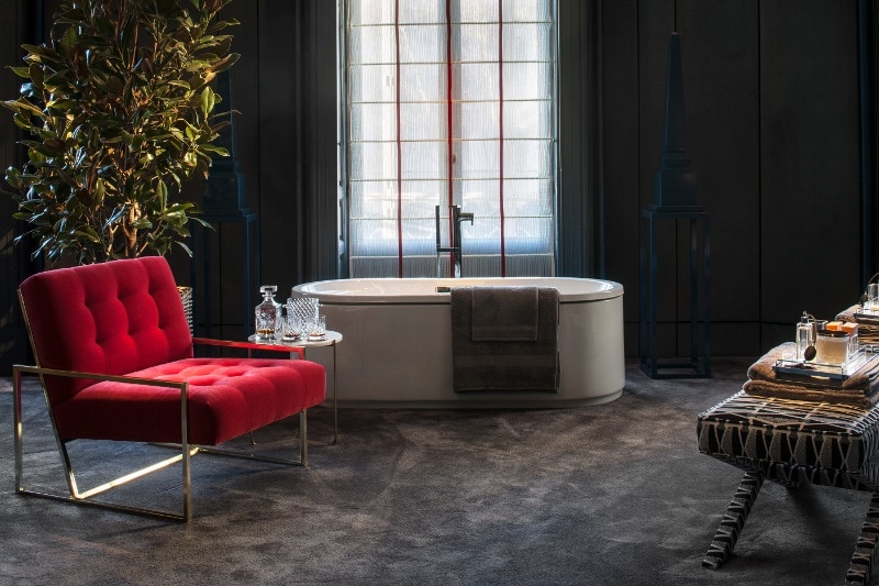 Большая и элегантная дизайнерская ванная комната с модным креслом